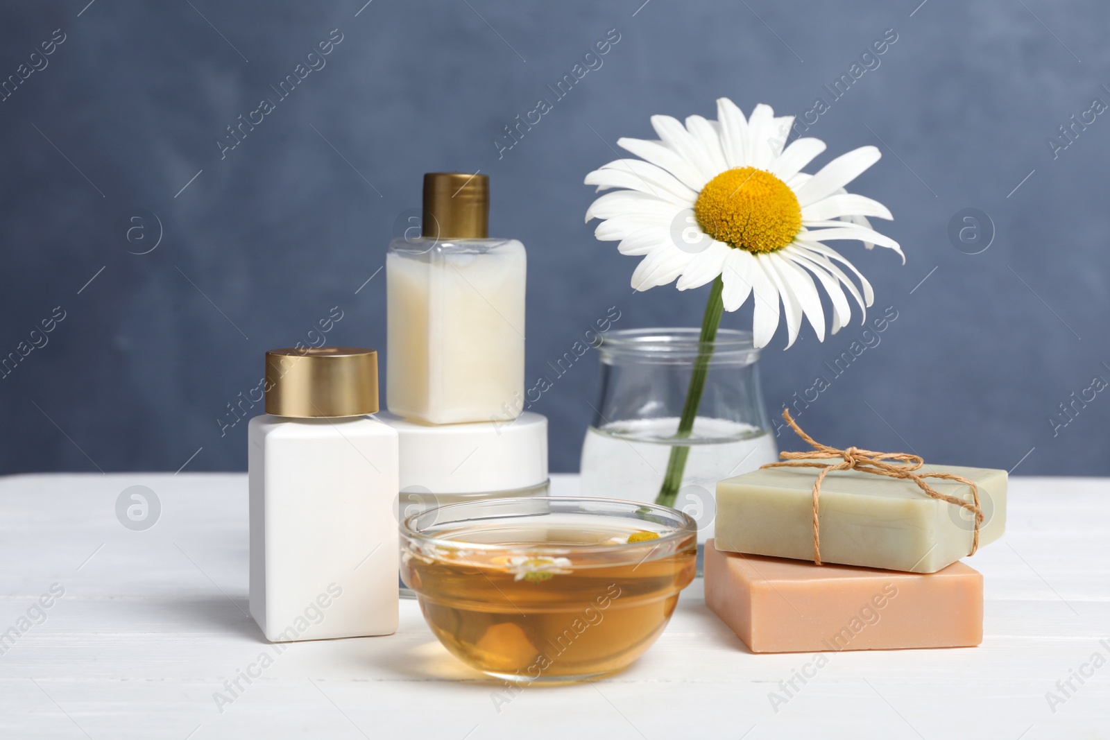 Photo of Composition with chamomile flower and cosmetic products on white wooden table