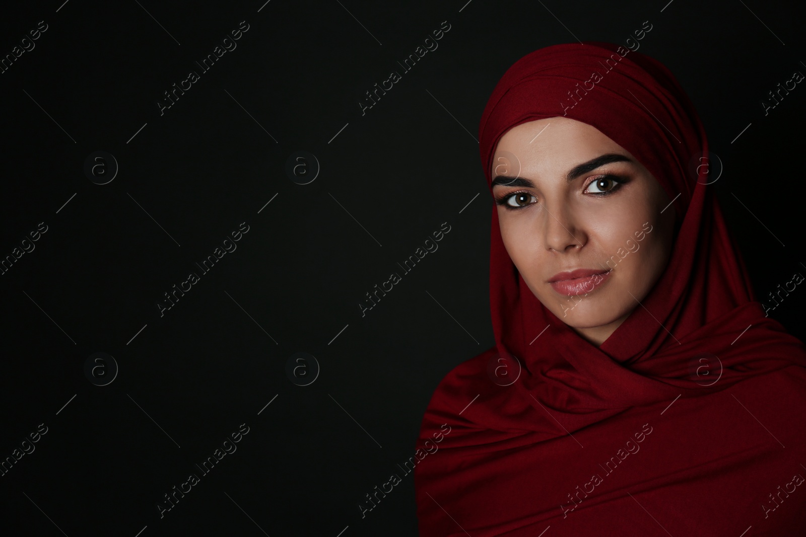 Photo of Portrait of Muslim woman in hijab on dark background. Space for text