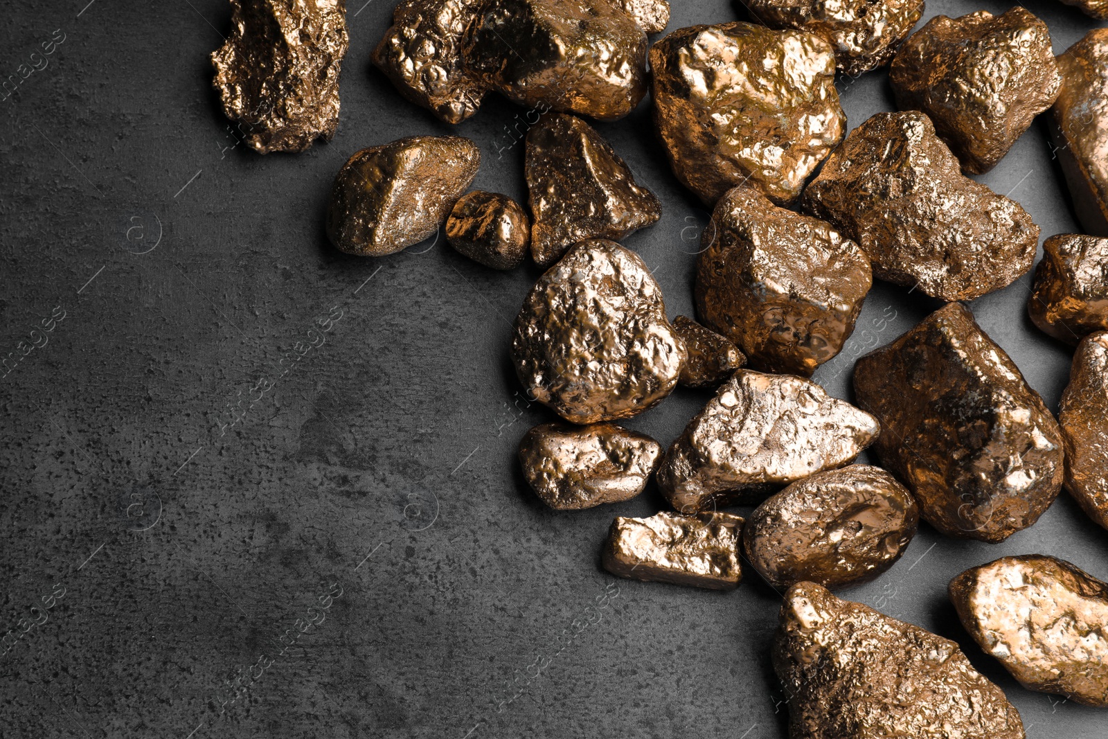 Photo of Pile of gold nuggets on grey table, flat lay. Space for text