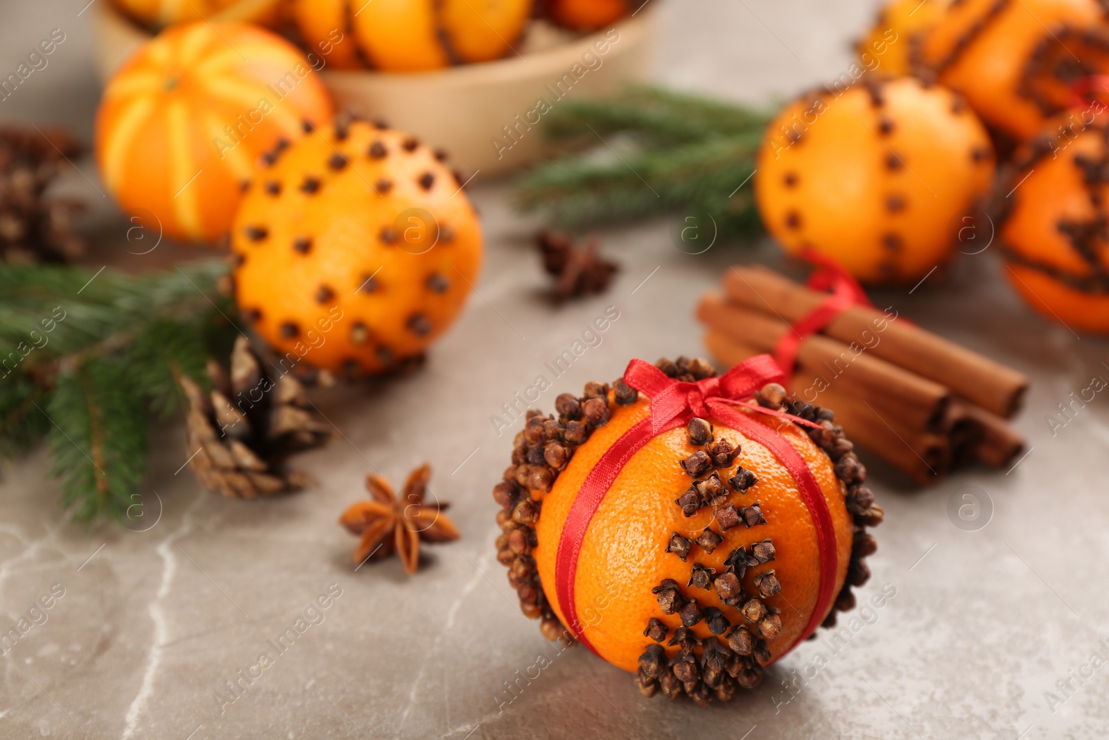 Photo of Pomander ball made of fresh tangerine and cloves on grey table, space for text