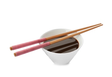 Photo of Bowl of soy sauce and chopsticks on white background