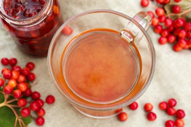 Photo of Cup of tea, jam and ripe viburnum berries on table, closeup