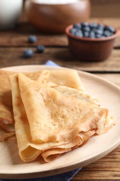 Delicious crepes served on wooden table, closeup