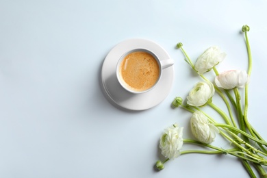 Photo of Cup of hot coffee and beautiful ranunculus flowers on white background