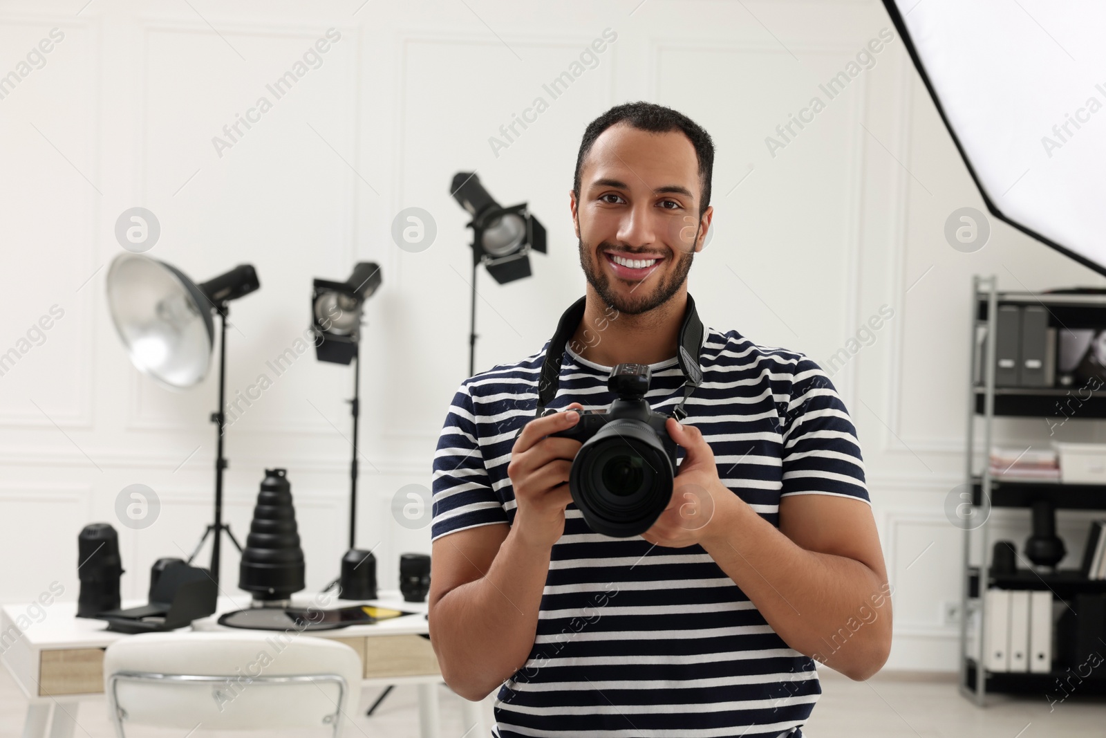 Photo of Young professional photographer with camera in modern photo studio, space for text