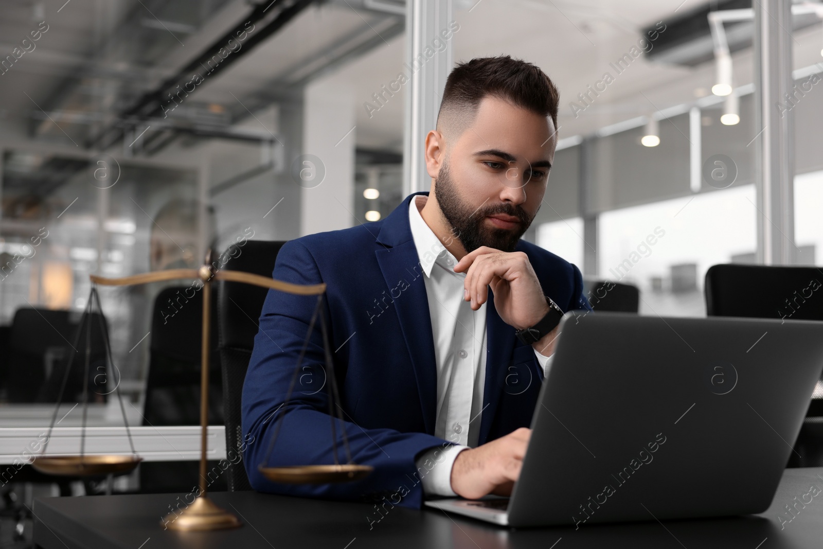 Photo of Serious lawyer working with laptop at table in office