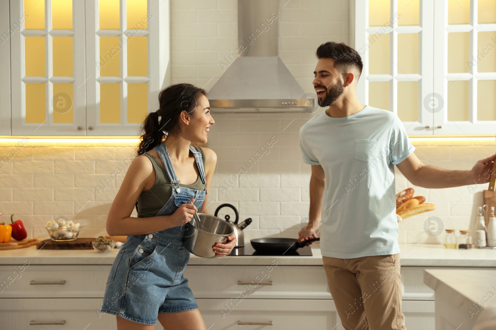 Photo of Lovely young couple dancing while cooking together in kitchen