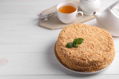 Photo of Delicious Napoleon cake served on white wooden table. Space for text