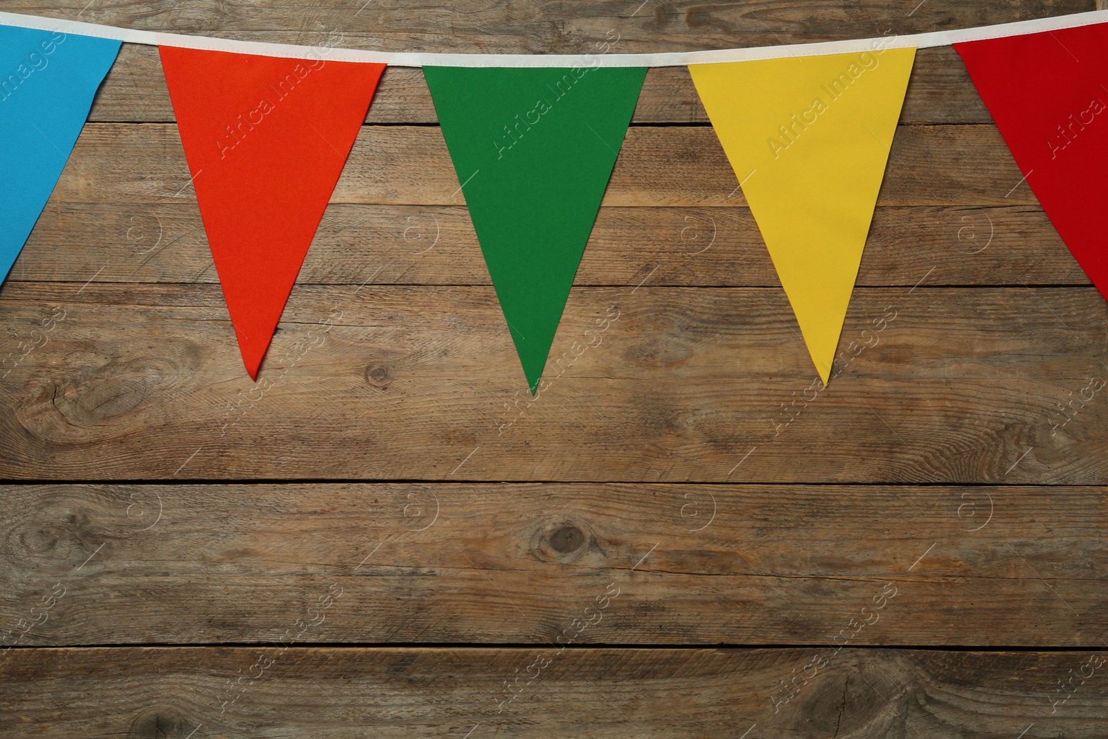 Photo of Bunting with colorful triangular flags on wooden background, space for text