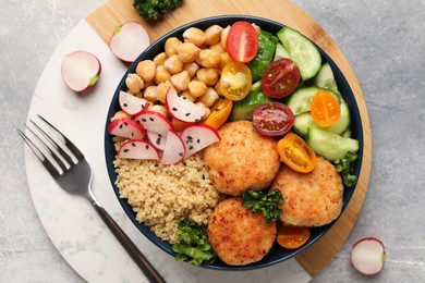 Delicious vegan bowl with chickpeas, cutlets and radish on grey table, flat lay