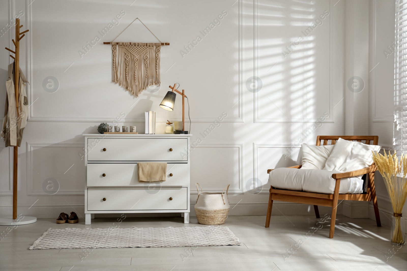 Photo of Stylish room interior with white chest of drawers and comfortable armchair