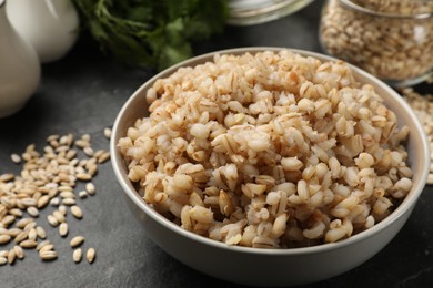 Photo of Tasty pearl barley porridge in bowl on dark table, closeup