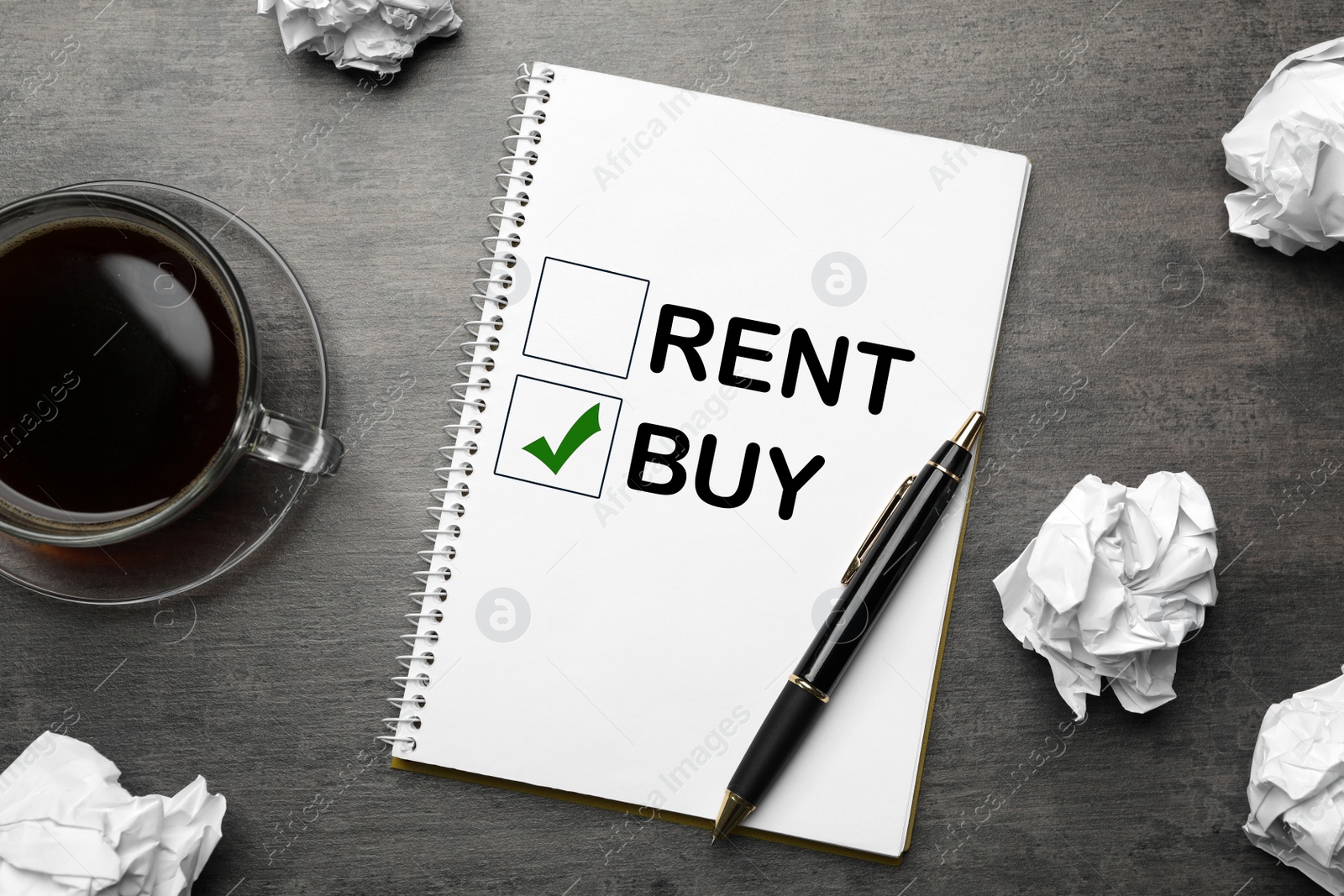 Image of Buy or rent - choice concept. Flat lay composition with crumpled paper balls and notebook on grey table