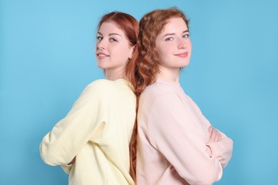 Photo of Portrait of beautiful young redhead sisters on light blue background