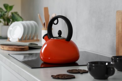 Photo of Red kettle with whistle on cooktop in kitchen