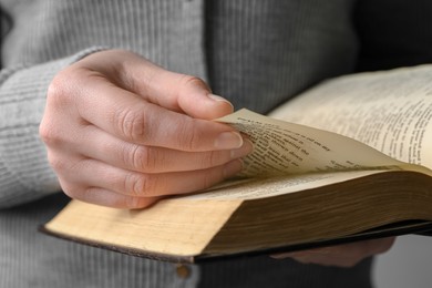 Woman reading Bible against grey background, closeup