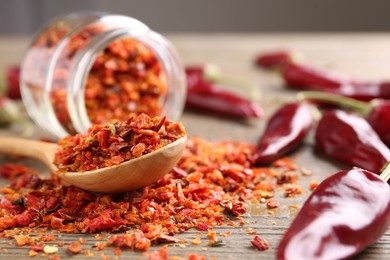 Photo of Chili pepper flakes and pods on wooden table, closeup. Space for text