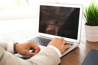 Photo of Man in office wear using laptop at table indoors