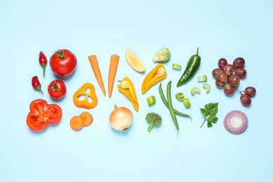 Photo of Fresh organic fruits and vegetables on light blue background, flat lay