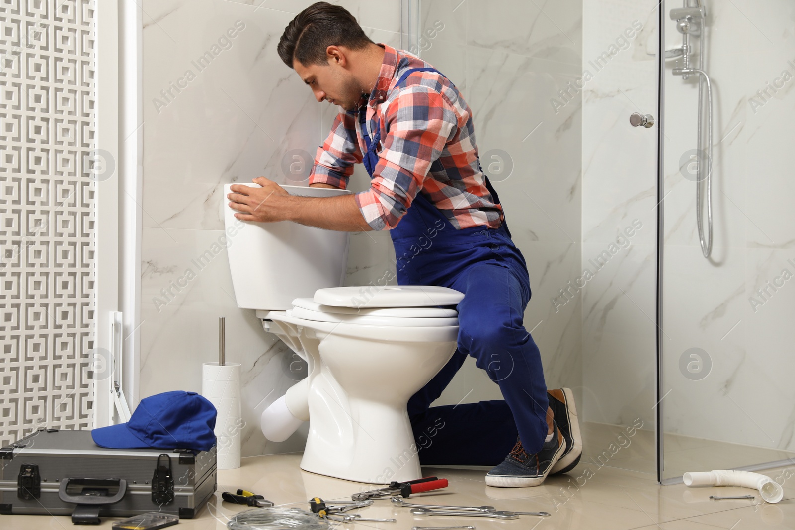 Photo of Professional plumber working with toilet bowl in bathroom