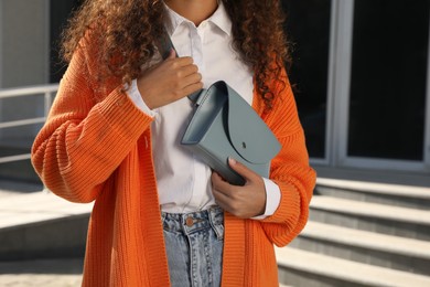 Photo of Young African American woman with stylish waist bag on city street, closeup