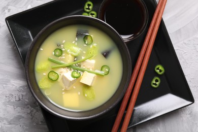 Photo of Bowl of delicious miso soup with tofu on light grey table, top view