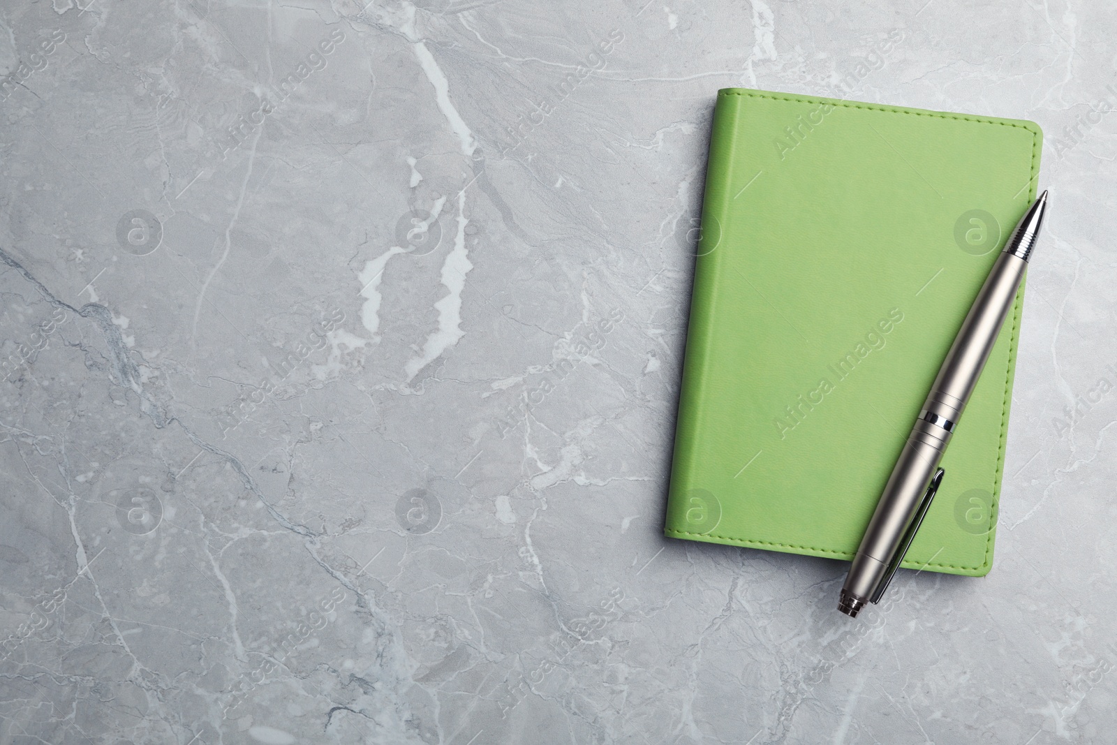 Photo of Stylish notebook and pen on marble table, top view. Space for text