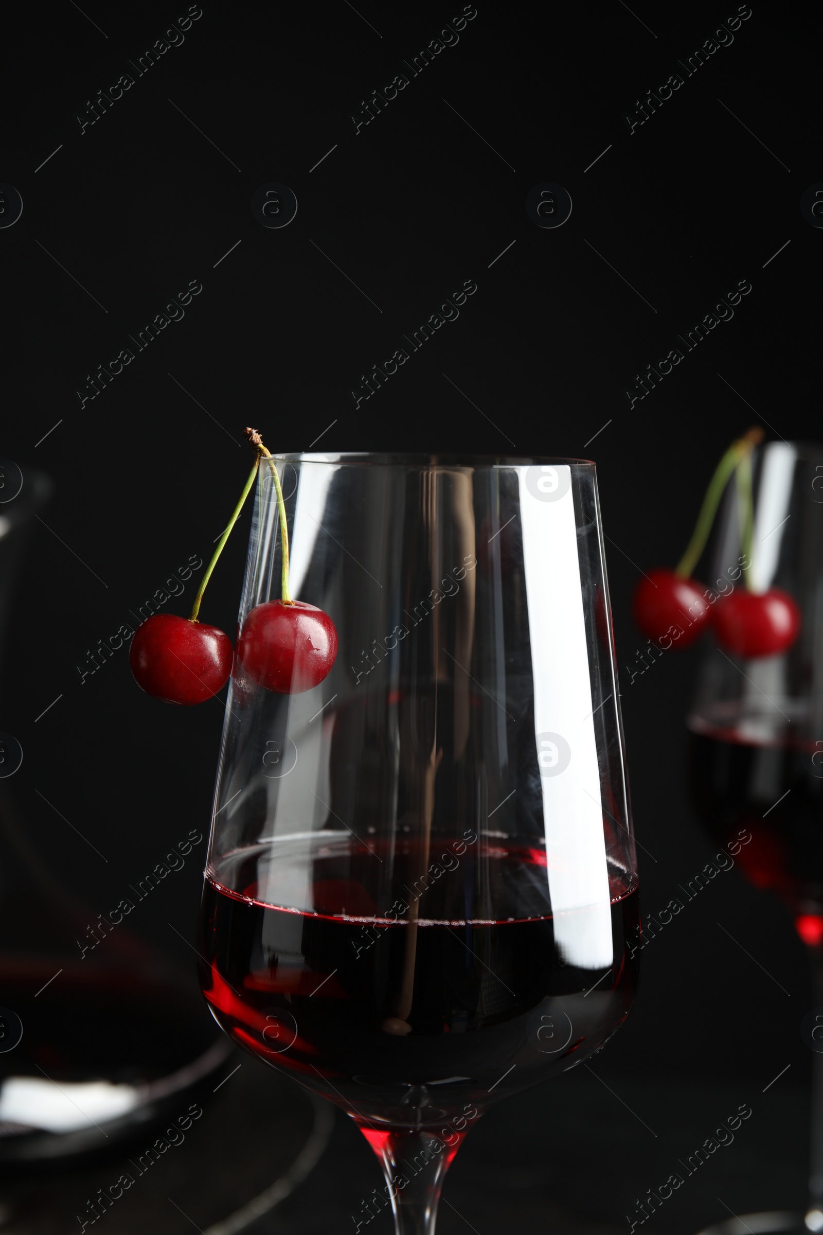 Photo of Delicious cherry wine with ripe juicy berries on black background