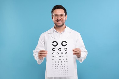 Photo of Ophthalmologist with vision test chart on light blue background