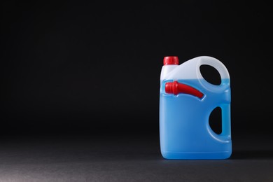 Photo of Plastic canister with blue liquid on black background. Space for text