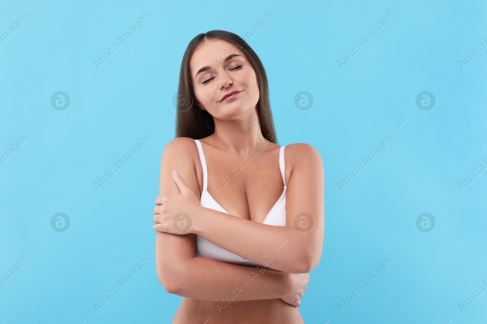 Photo of Portrait of young woman with beautiful breast on light blue background