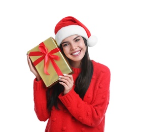 Happy young woman in Santa hat holding Christmas gift on white background