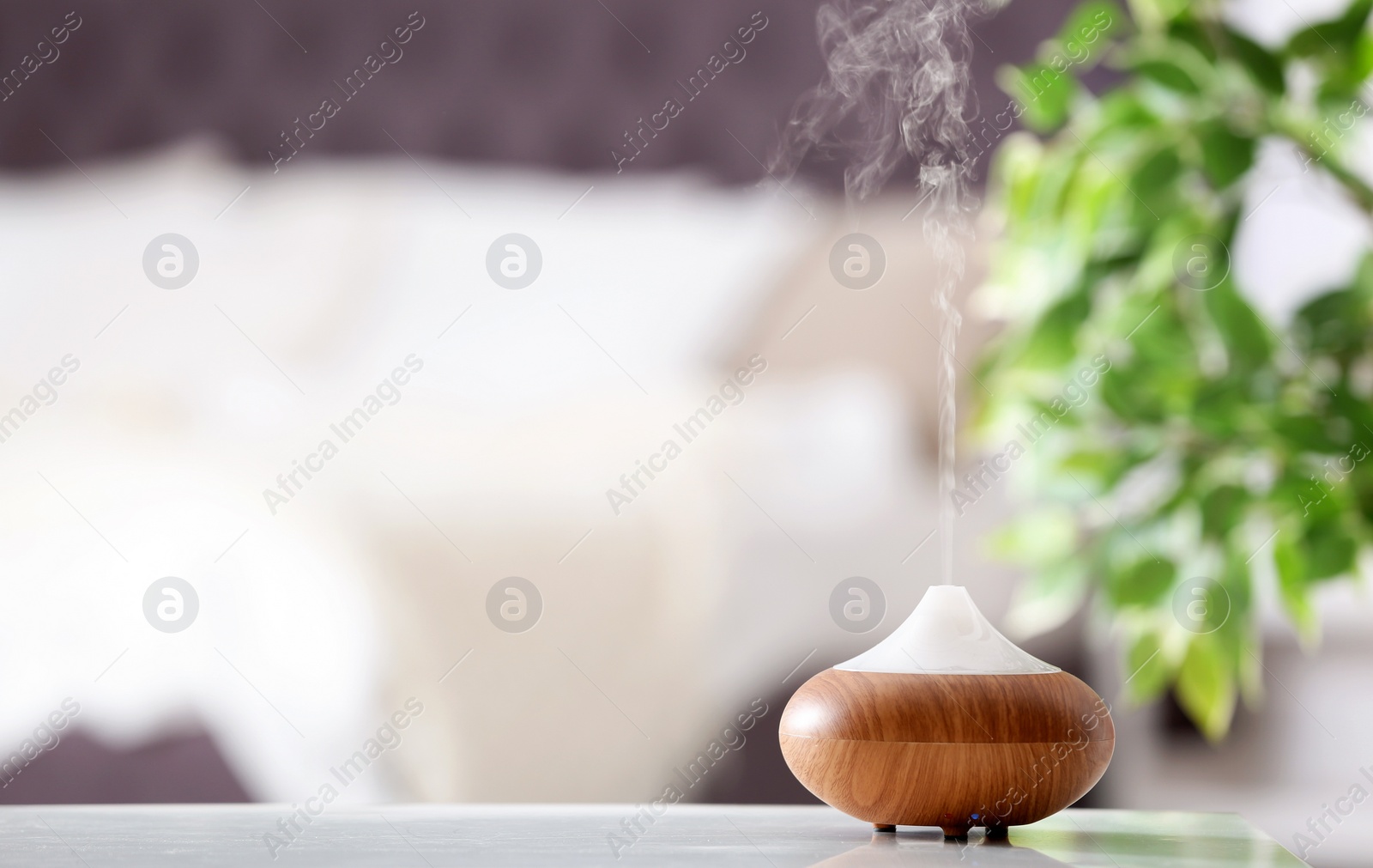 Photo of Aroma oil diffuser lamp on table against blurred background