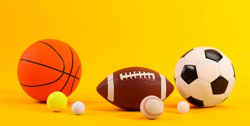 Photo of Many different sports balls on yellow background. Banner design