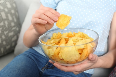 Woman eating chips while watching TV, closeup view