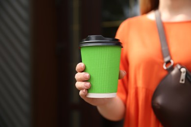 Woman with takeaway coffee cup outdoors, closeup. Space for text