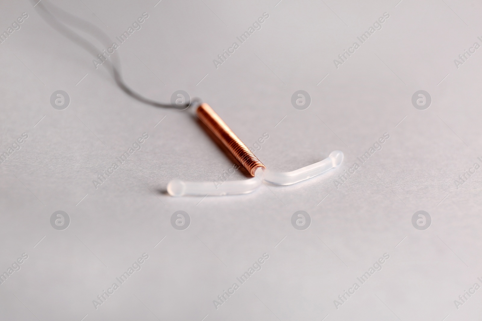 Photo of T-shaped intrauterine birth control device on light background