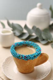 Delicious edible biscuit cup of espresso decorated with sprinkles on table