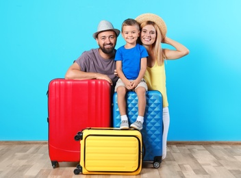 Photo of Happy family with suitcases near color wall. Vacation travel