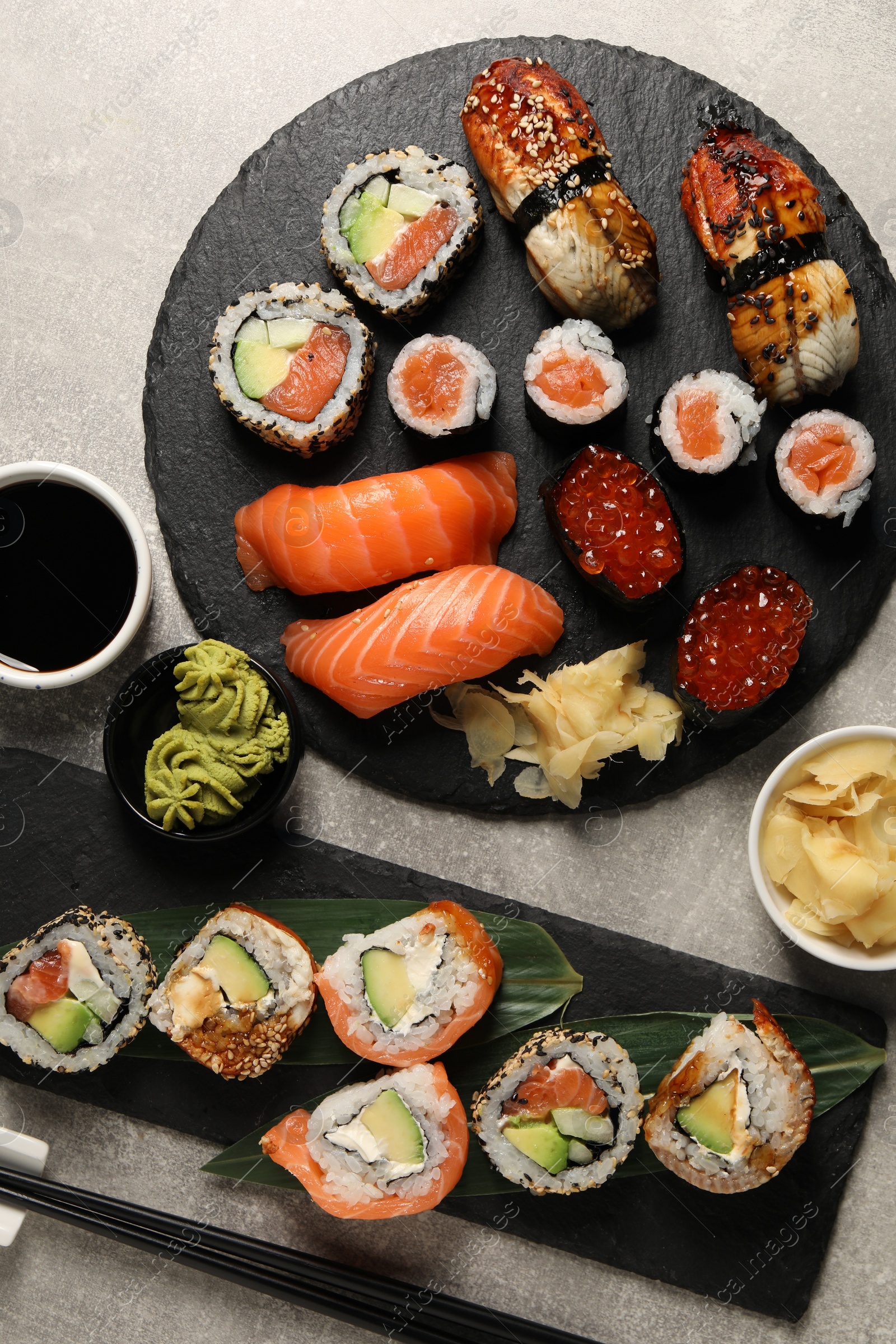 Photo of Different tasty sushi rolls on light grey table, flat lay