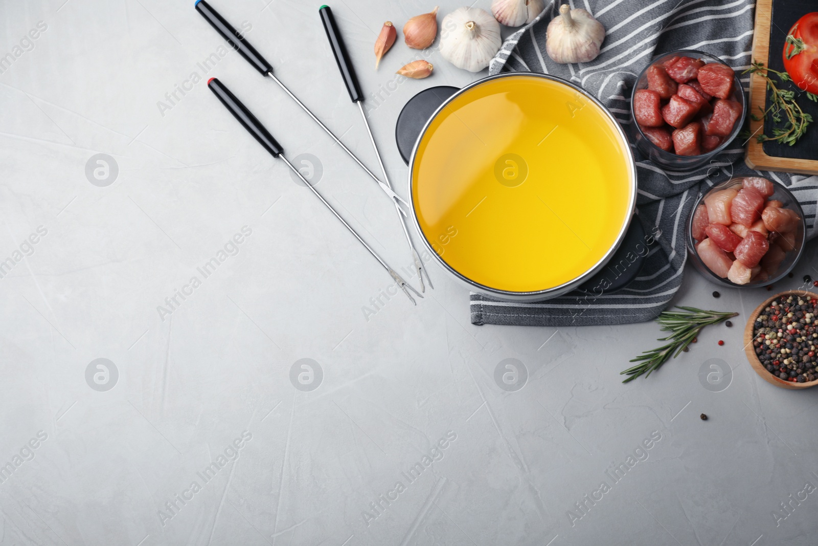 Photo of Flat lay composition with fondue pot, meat and space for text on table