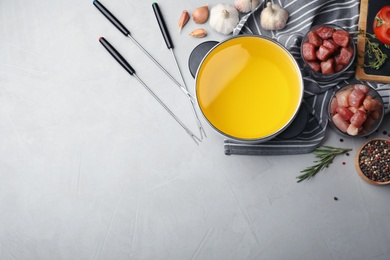 Flat lay composition with fondue pot, meat and space for text on table