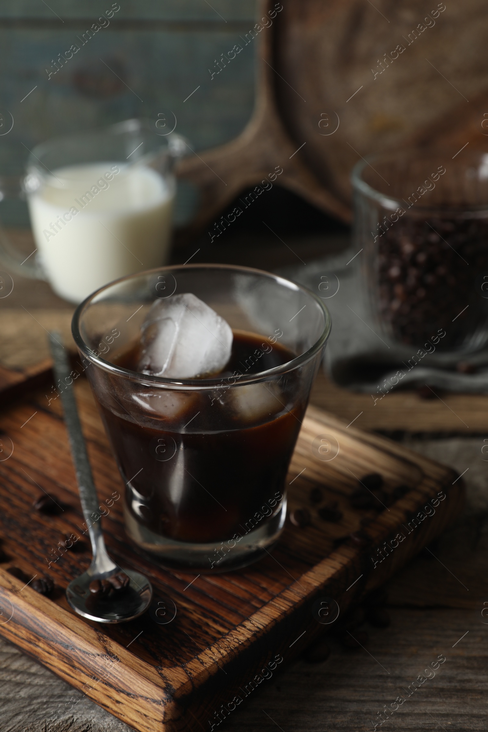 Photo of Glass of delicious iced coffee and beans on wooden table