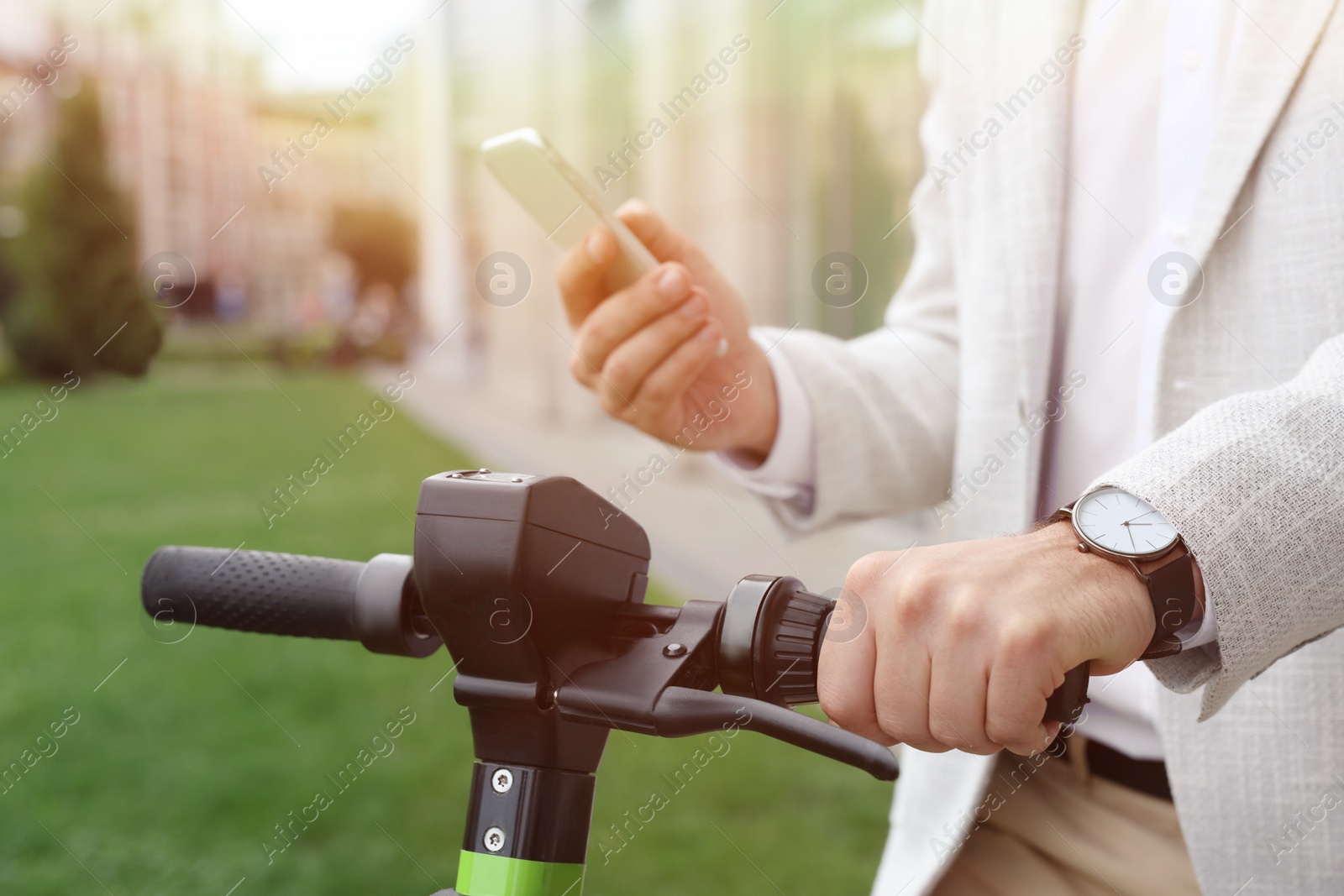 Photo of Businessman with modern kick scooter using smartphone on city street, closeup