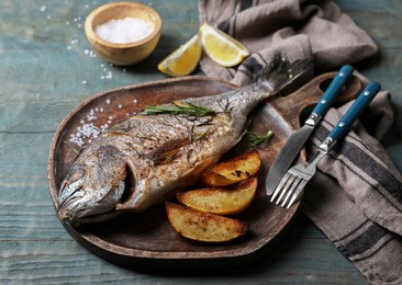 Photo of Delicious baked fish served on wooden rustic table. Seafood