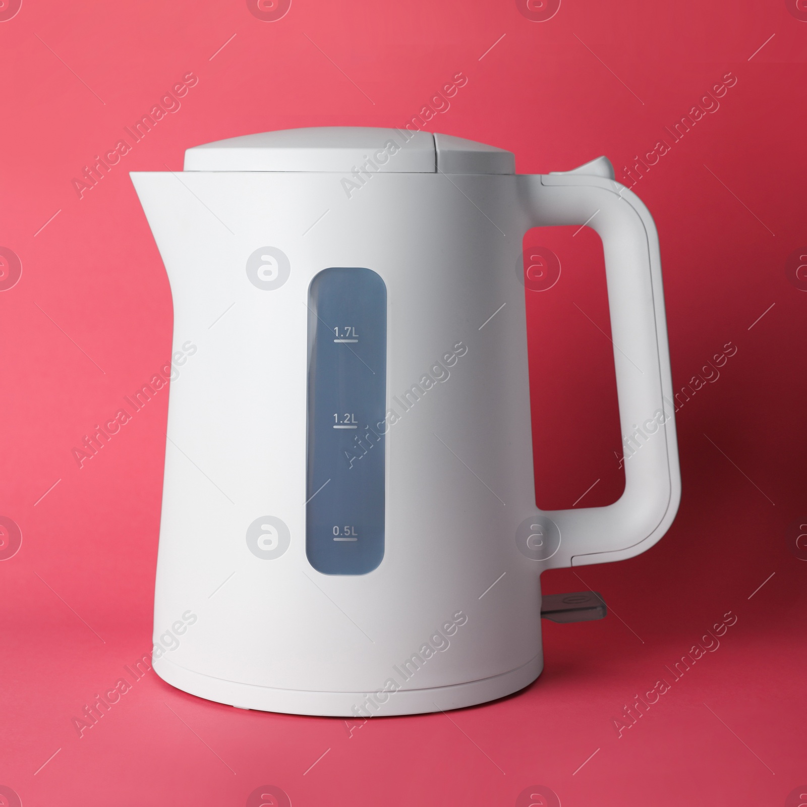 Photo of New modern electric kettle on red background