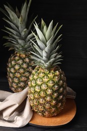 Photo of Whole ripe pineapples on black wooden table