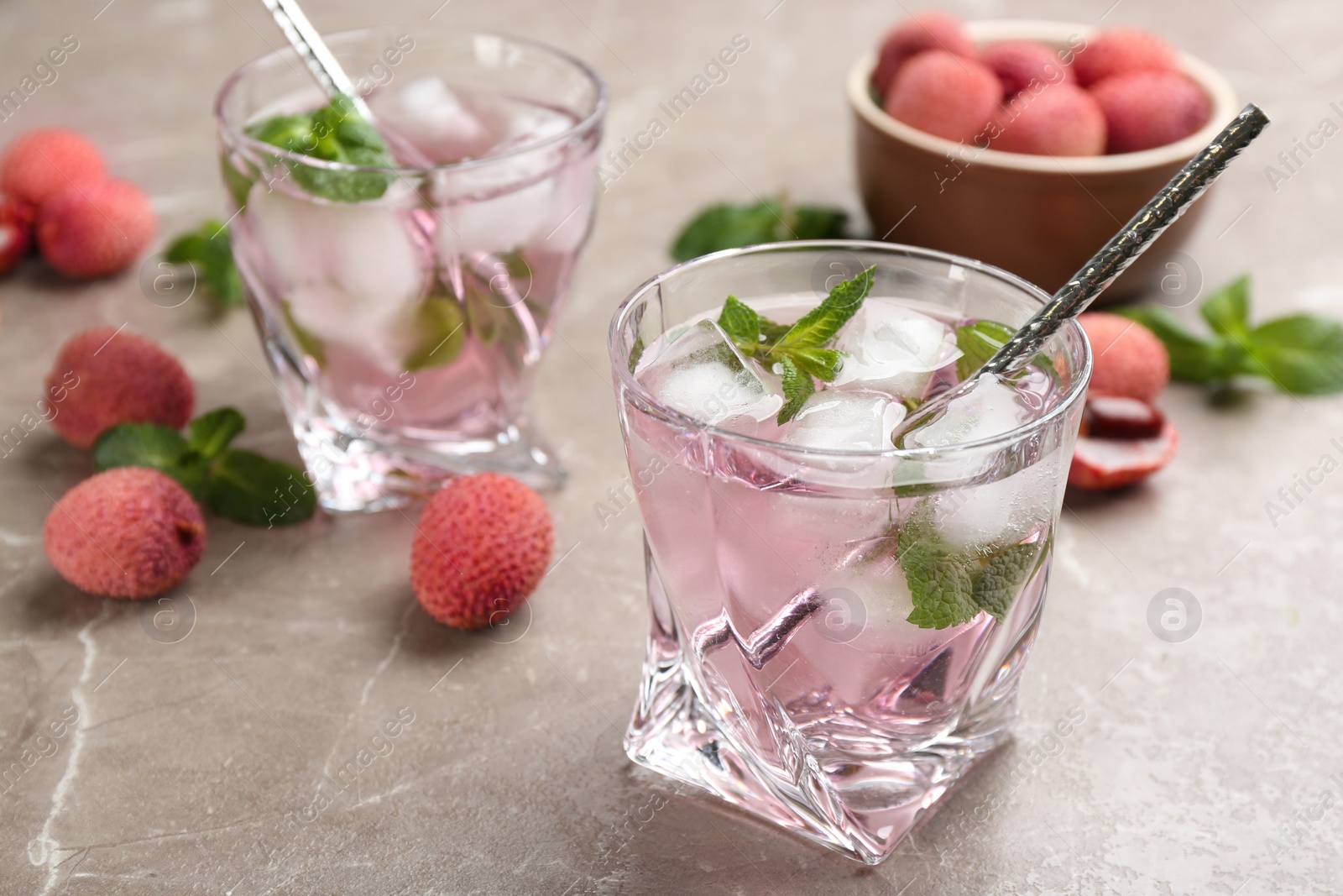 Photo of Lychee cocktail with mint and ice on grey table, space for text