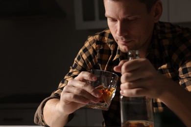 Photo of Addicted man with alcoholic drink in kitchen, closeup