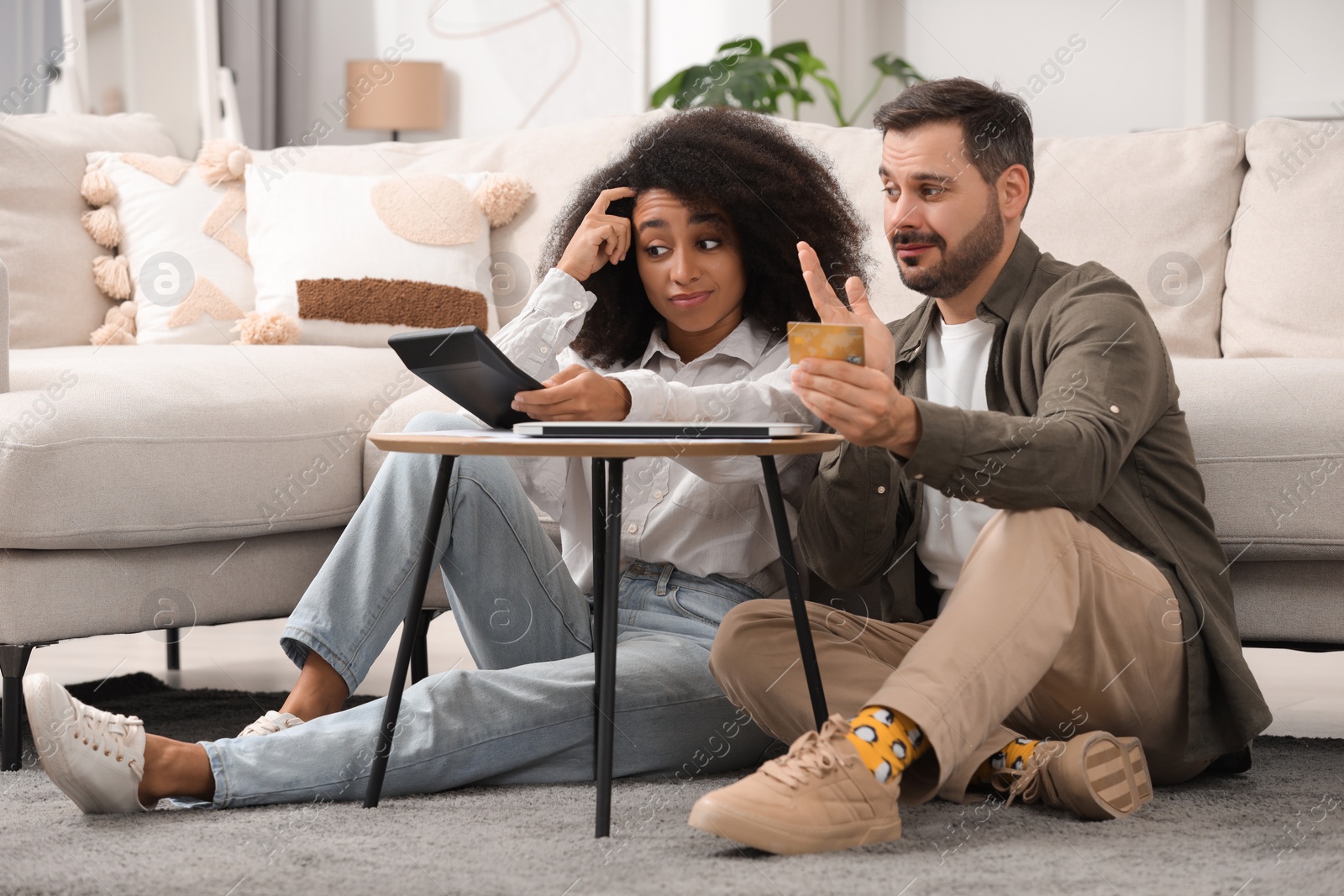 Photo of Confused couple with calculator and credit card planning budget at home. Debt problem